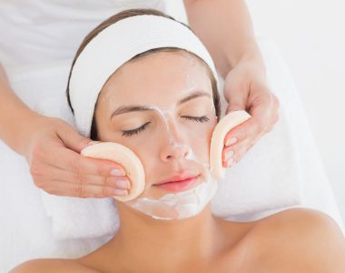 Hand cleaning woman's face with cotton swabs at spa center